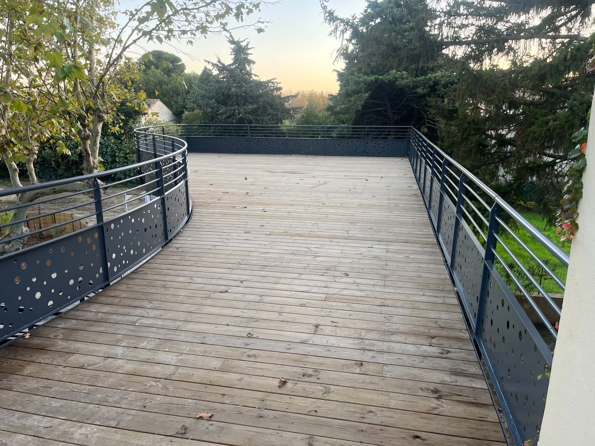 Terrasse en bois bordée d’un garde-corps métallique